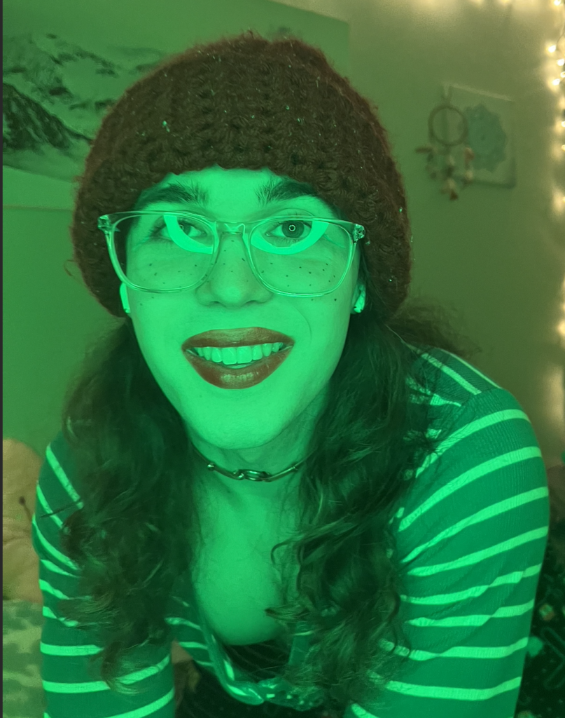 Emily is in green light and smiling at the camera.